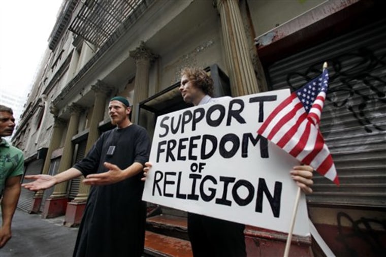 Abdul Malik, center, an American Muslim from Philadelphia, and Matt Sky, right, a Web developer from Manhattan, N.Y., stand in front of a proposed site for an Islamic cultural center as they explain their support for its construction to passers-by in New York on Monday. 